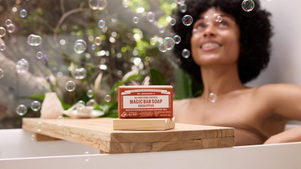 Woman in bath with Dr. Bronner's Magic Bar Soap.