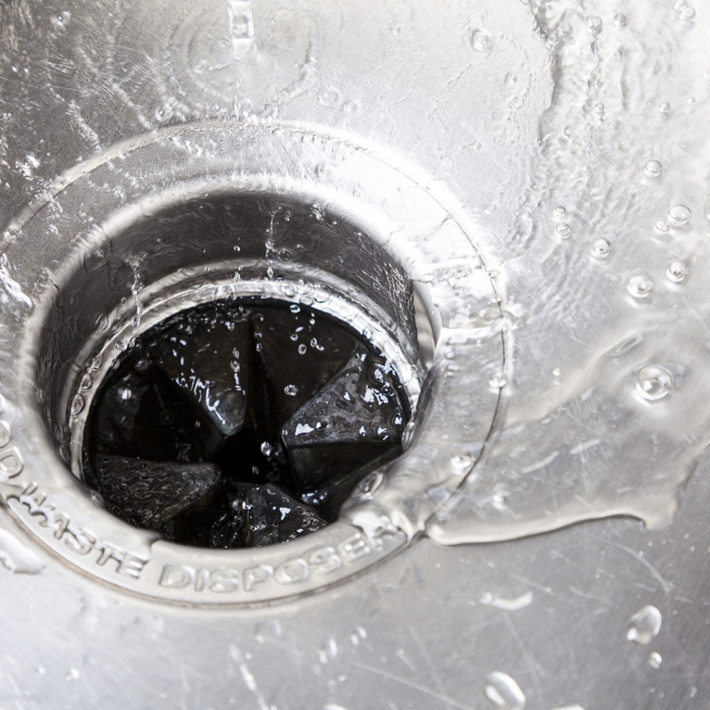 Clean water going down the drain in a stainless steel sink.