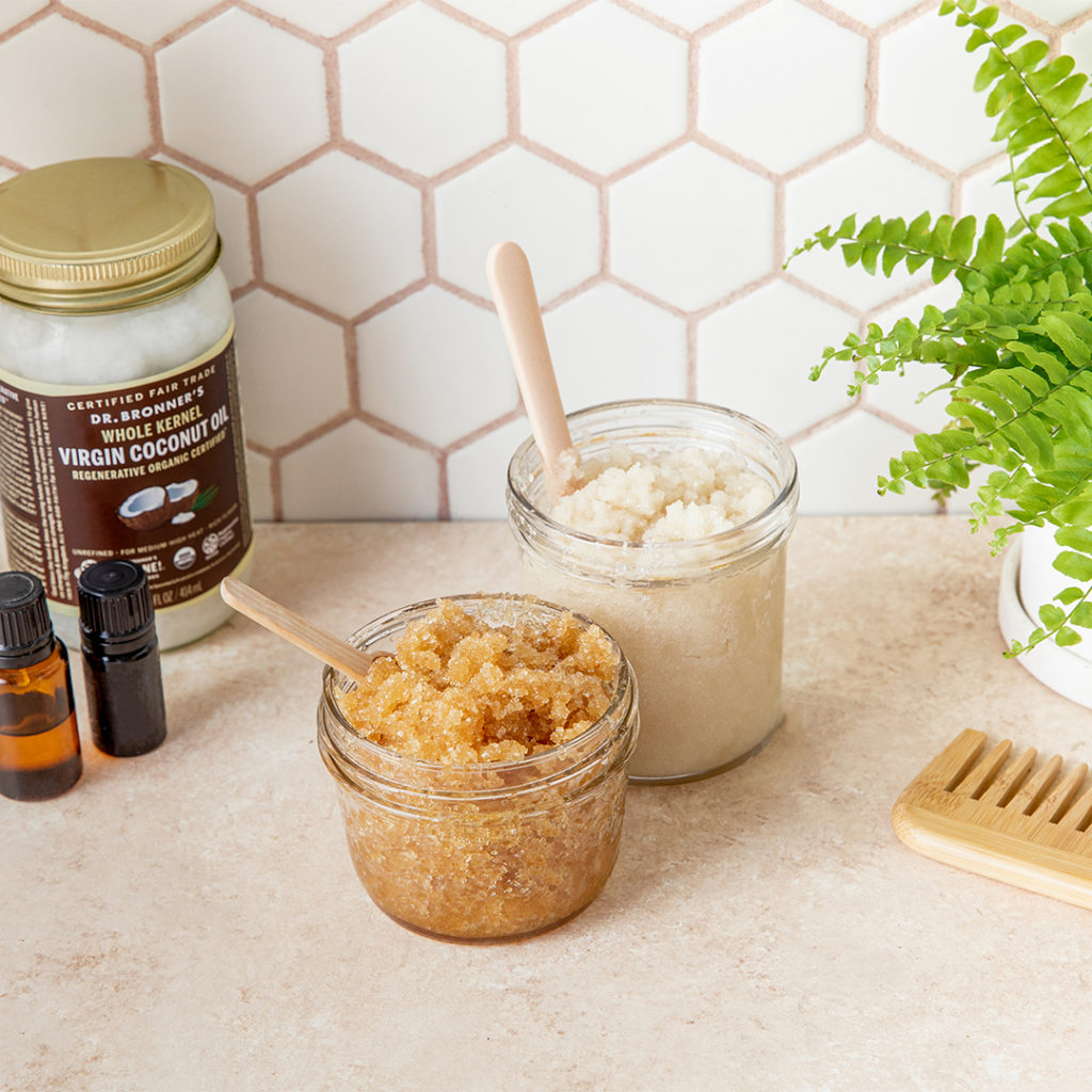 Two glass jars filled with body scrubs made of sugar and coconut oil.