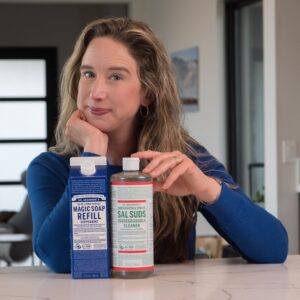 Lisa sitting at counter with Dr. Bronner's Castile Magic Soap and Sal Suds.
