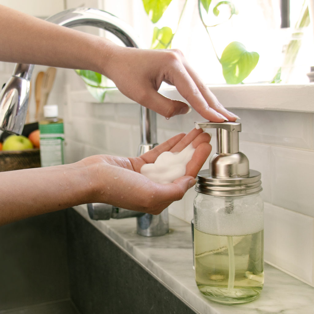 Person using foaming hand soap at a sink. foaming hand soap with Dr. Bronner's soaps