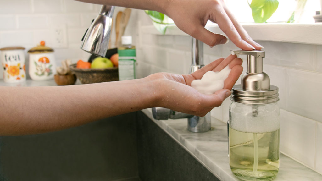 Person using foaming hand soap at a sink. foaming hand soap with Dr. Bronner's soaps