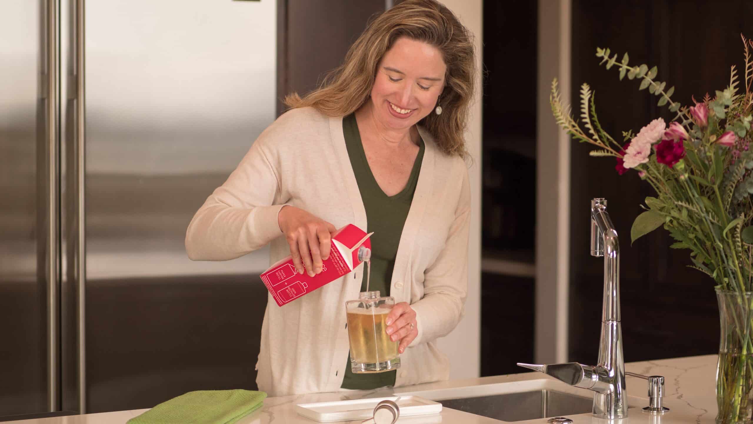 Lisa filling up a foaming pump with a Dr. Bronner's Magic Soap refill carton.