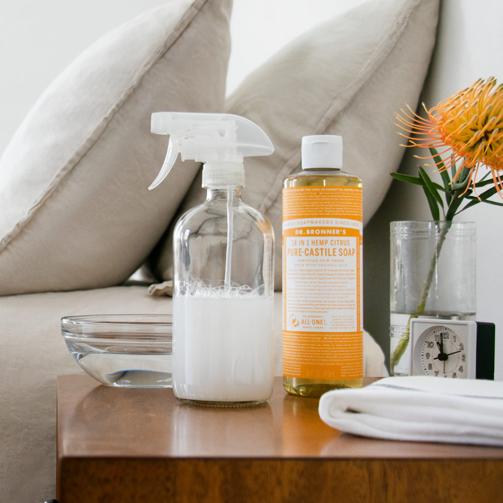 Dr. Bronner's Castile Soap and spray bottle on a table. wipe-off body cleaning spray