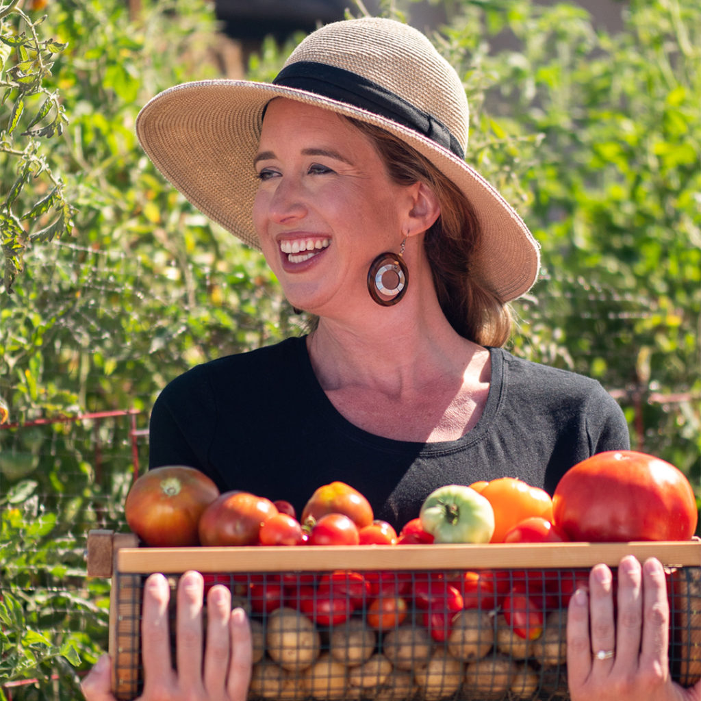 Lisa Bronner holding a basket of tomatoes from the garden. how to garden using regenerative practices