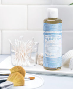 A bottle of Dr. Bronner's Pure-Castile Soap and makeup brushes.