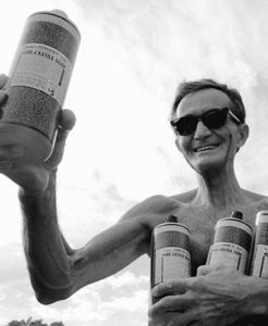 Black and white photo of Dr. Emanual Bronner holding bottles of his Pure-Castile Soap.