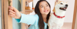 Smiling girl and her dog looking out an open window.