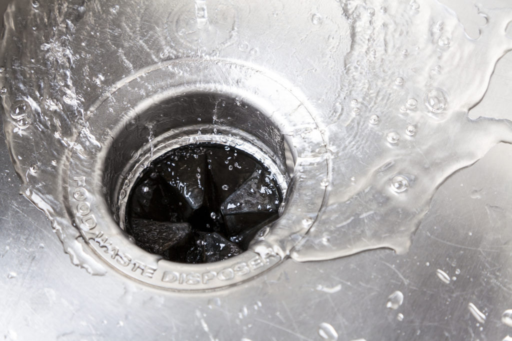 Clean water going down the drain in a stainless steel sink.