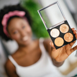 Woman holds a palette of eyeshadow towards the camera. Consumer product safety