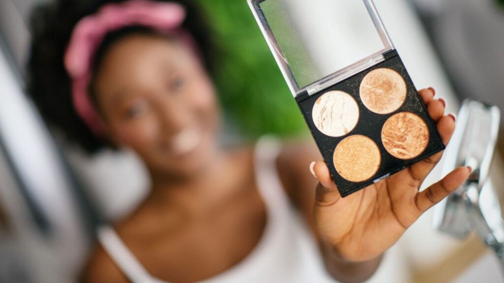 Woman holds a palette of eyeshadow towards the camera. Consumer product safety