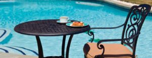 Outdoor table and chair next to a swimming pool. - cleaning patio furniture with Sal Suds