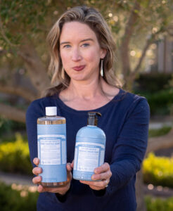 Lisa Bronner holding up Dr. Bronner's Castile Soap and Sugar Soap