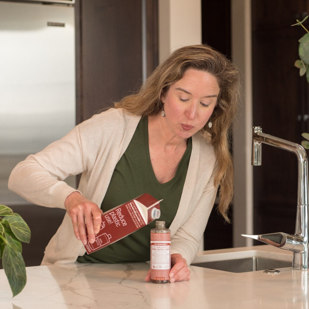 Lisa Bronner pouring Castile Soap from Dr. Bronner's Refill Carton into a bottle - New Carton Refill