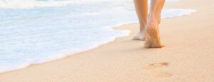 Feet walking on a sandy beach - Using Dr. Bronner's products at the beach