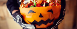 Child in costume holding a Halloween bucket filled with candy