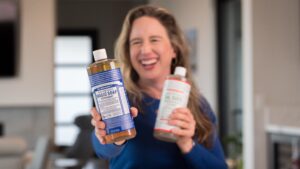 Lisa holding up Dr. Bronner's Magic Soap bottle and Sal Suds.