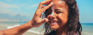 parent applying sunscreen to child's face at the beach