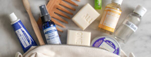 Various Dr. Bronner's products laid on table coming out of travel sized bag.
