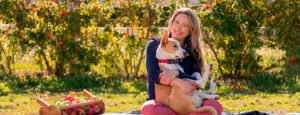 Lisa Bronner sitting outside, holding her brown and white dog