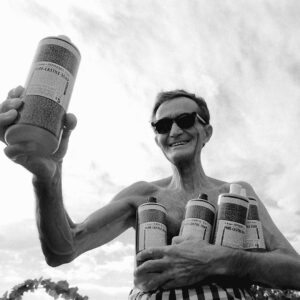 Dr. Bronner holding Castile Soap bottles.