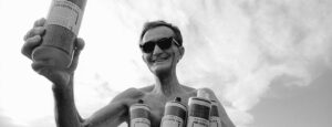 Dr. Bronner holding Castile Soap bottles.