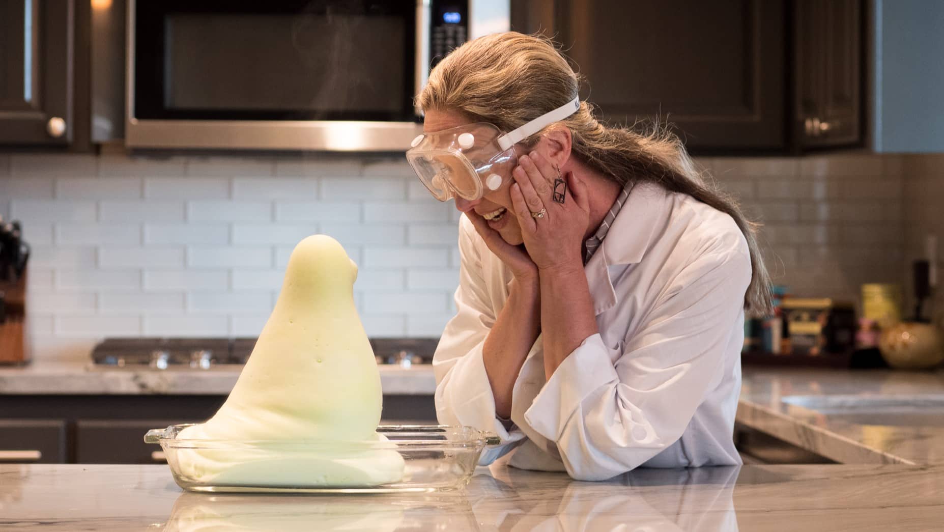 Looking smiling at science experiment on counter.