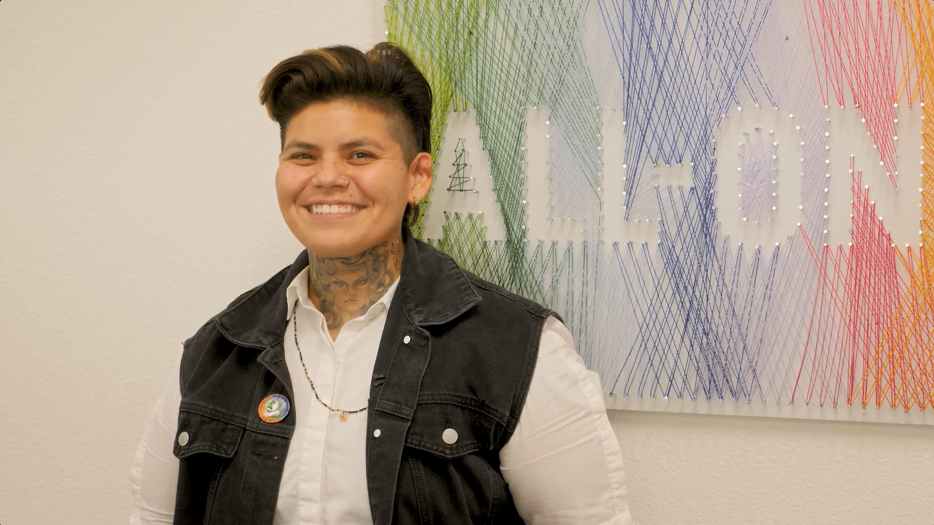 Monique standing and smiling by wall