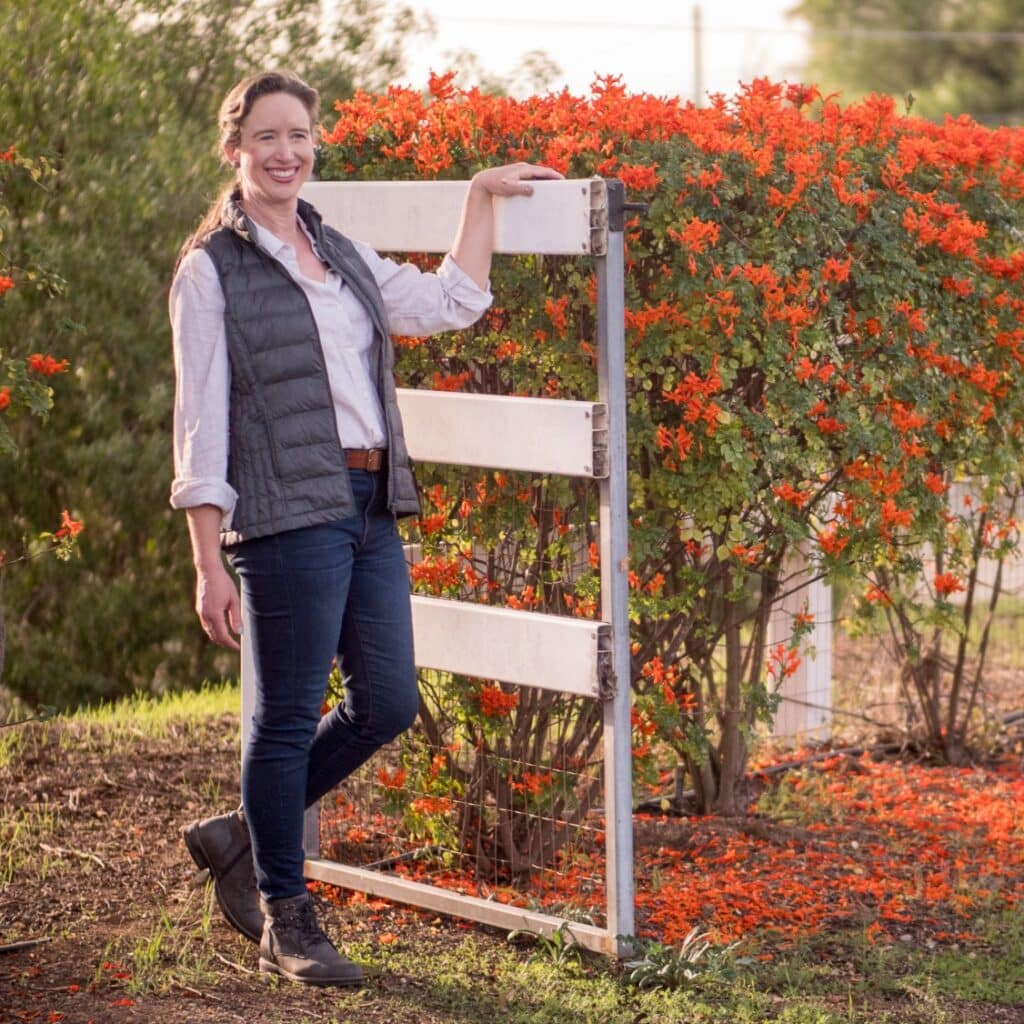 Lisa standing at a gate smiling.