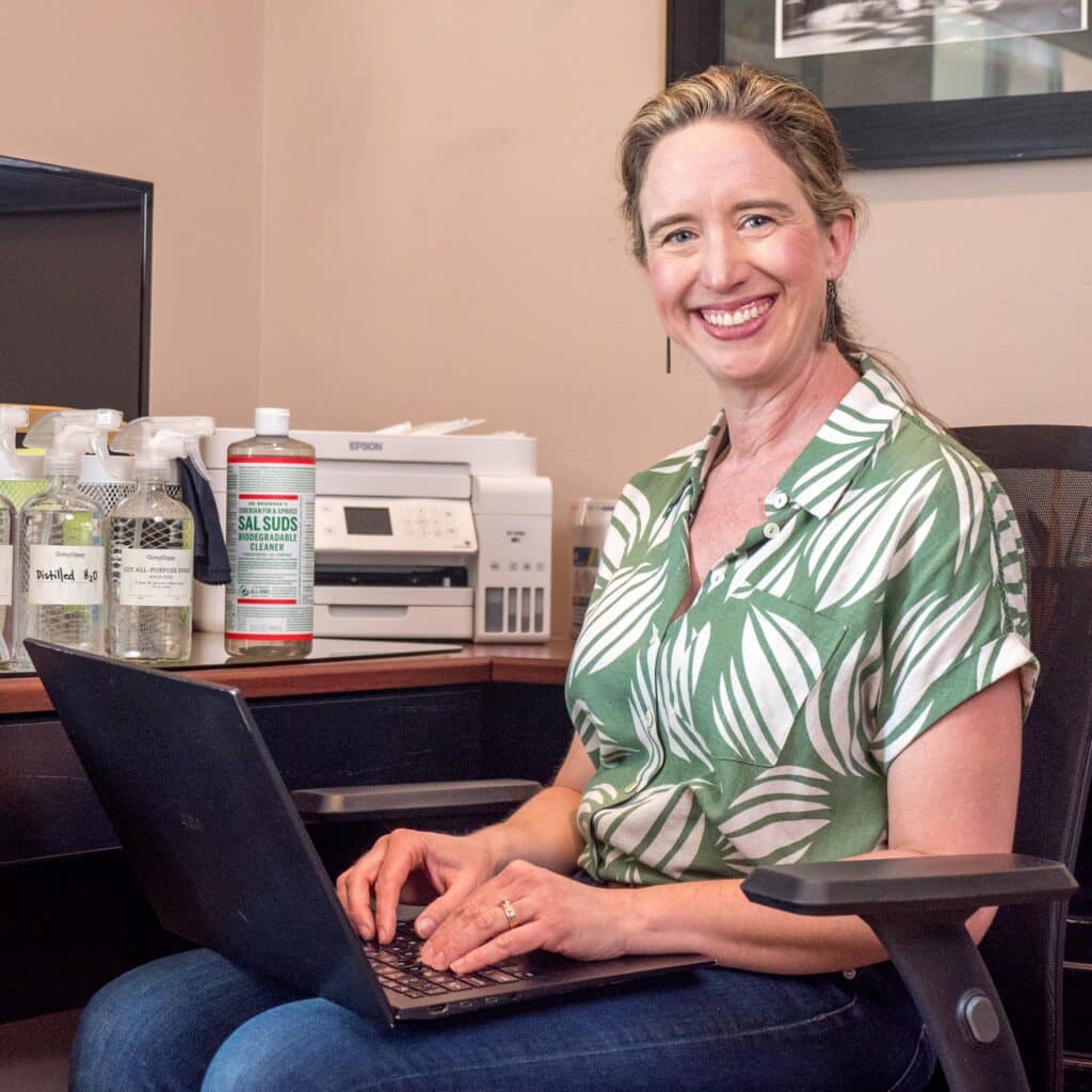 Lisa sitting at desk with Dr. Bronner's products.