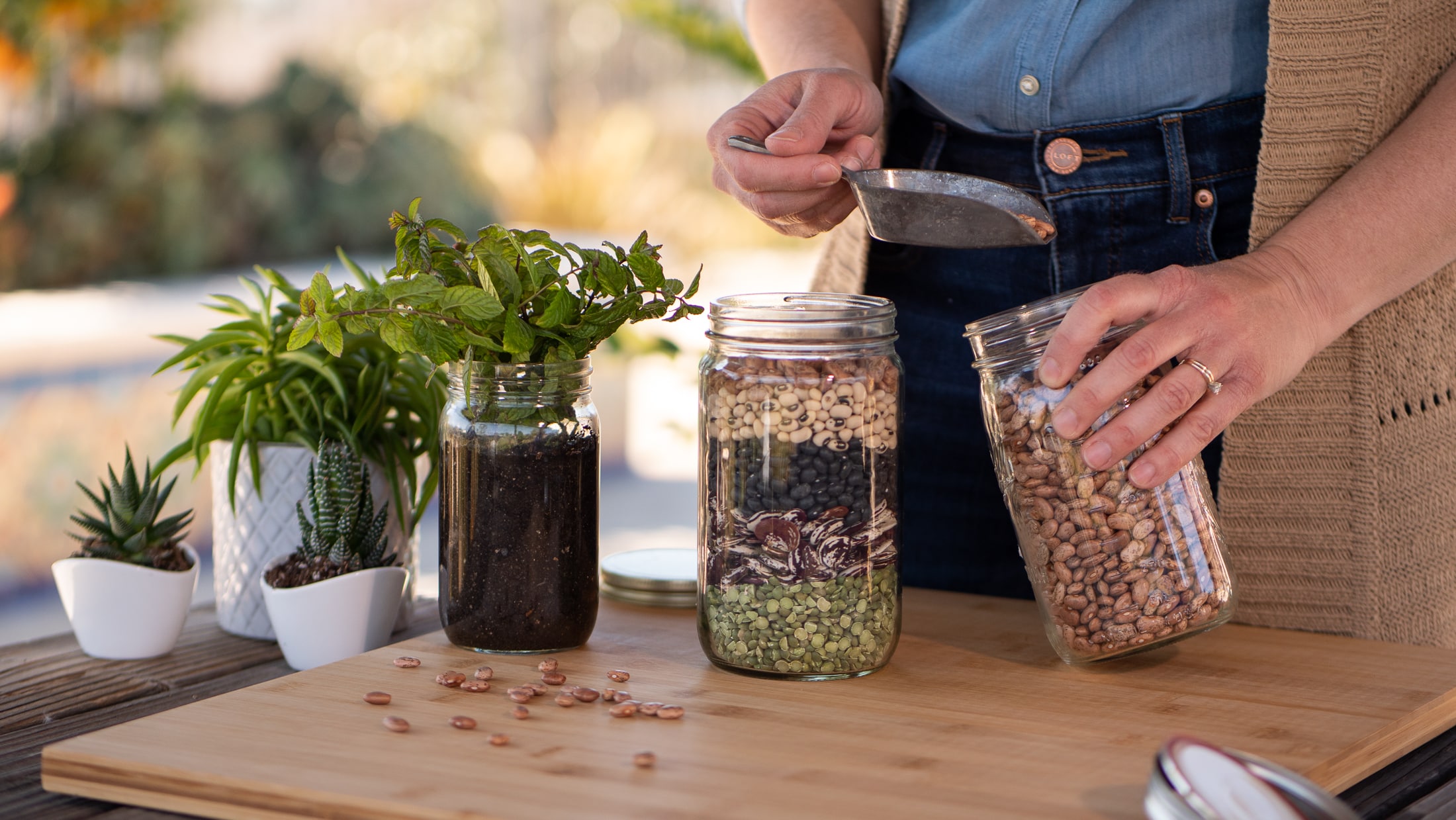 Hand refilling a glass jar full of beans.