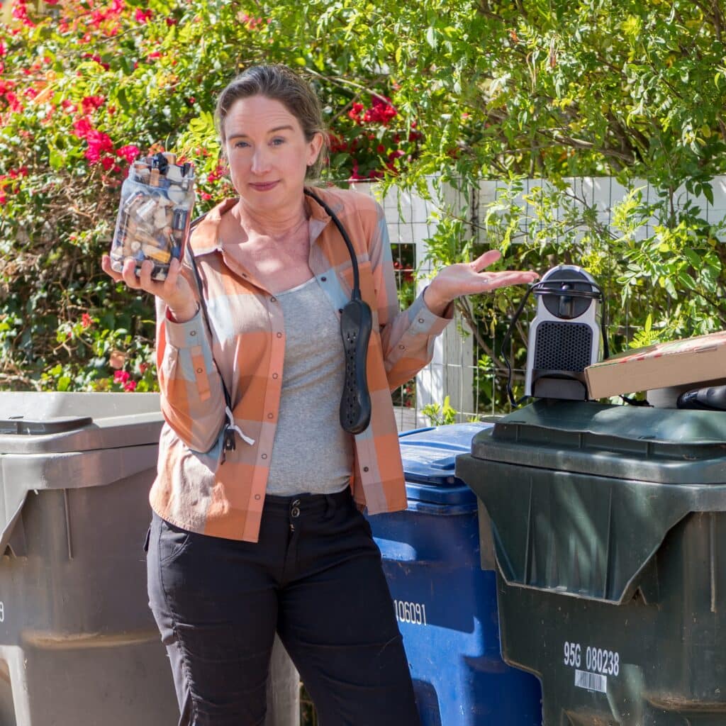 Lisa holding items by her trash can.